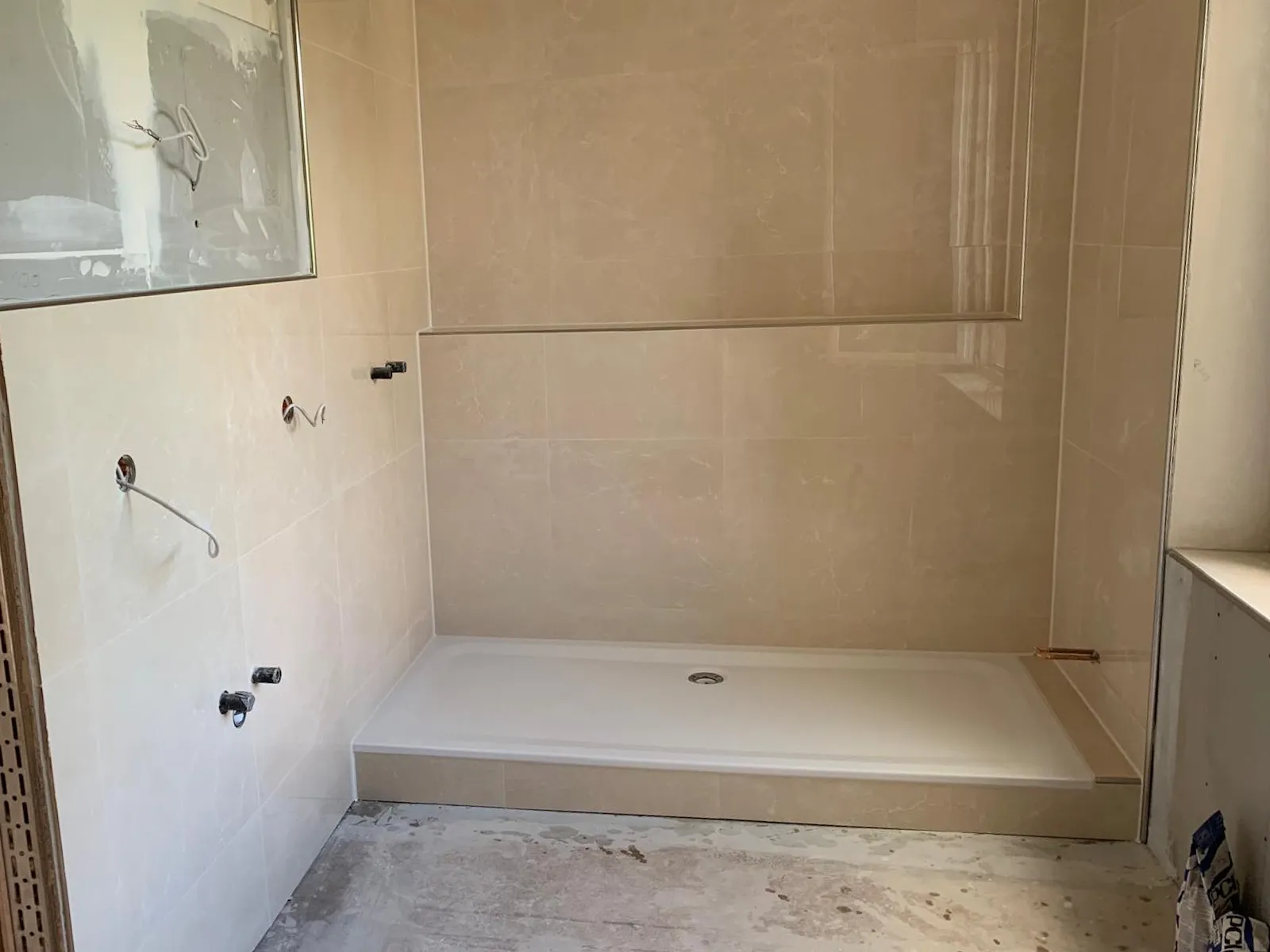 Neu geflieste Dusche in Beige mit flacher Duschwanne und verfliester Wandnische