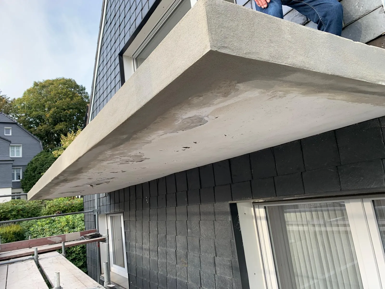 Instand gesetzte Unterseite der Balkonplatte am verschieferten Wohnhaus