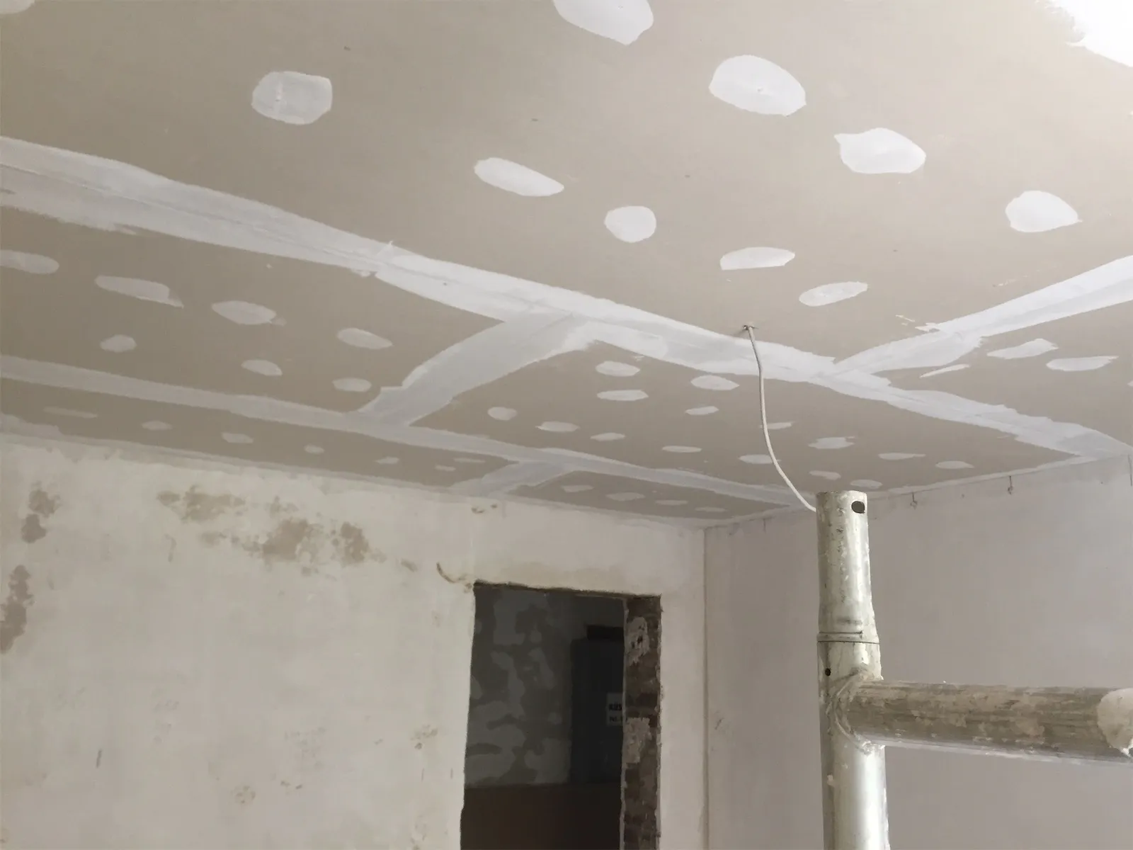 Neue Trockenbaudecke mit verspachtelten Fugen und Schraubstellen in einem Altbauraum während der Sanierung
